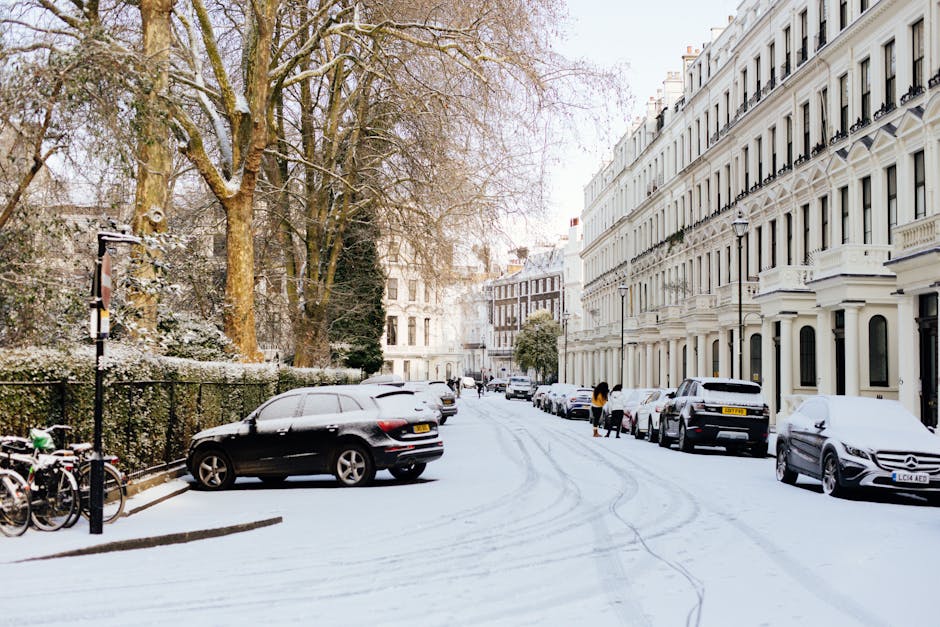 A busy street scene on New King's Road in Fulham, London, with a row of brick and white-painted terraced houses on the left side, some with shopfronts and signage. The pavement is occupied by pedestri